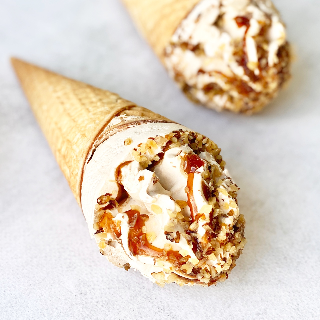 Мороженое сливочное с ароматом грецкого ореха, декорированное кленовым сиропом и грецким орехом в сахарном вафельном рожке с шоколадной глазурью изображение 1